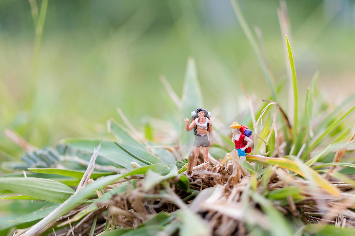 miniatuurreiziger met rugzakken die in het veld-, reis- en avontuurconcept lopen foto