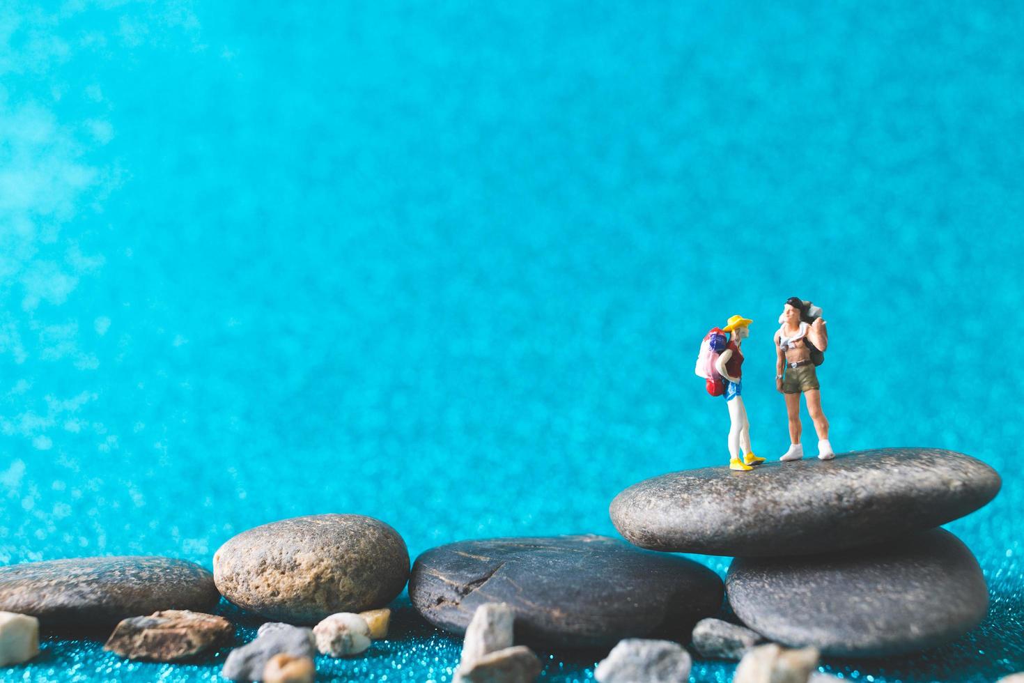 miniatuur backpackers, toeristenmensen op een blauwe glitterachtergrond foto