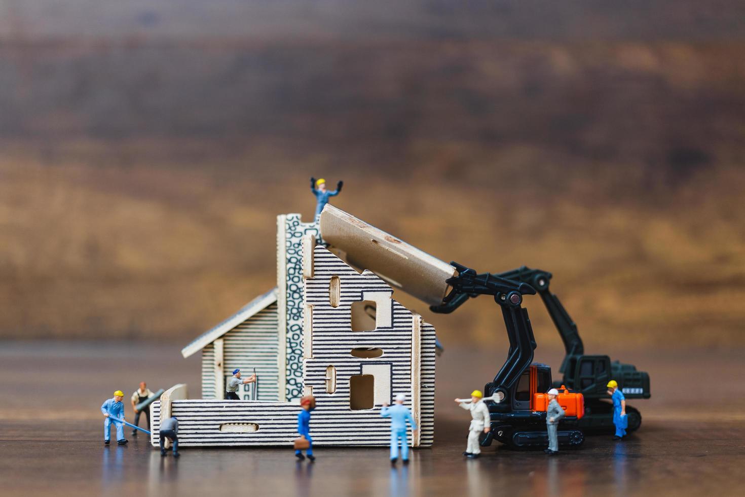 miniatuurarbeiders die een huis bouwen, het concept van de huisrenovatie foto