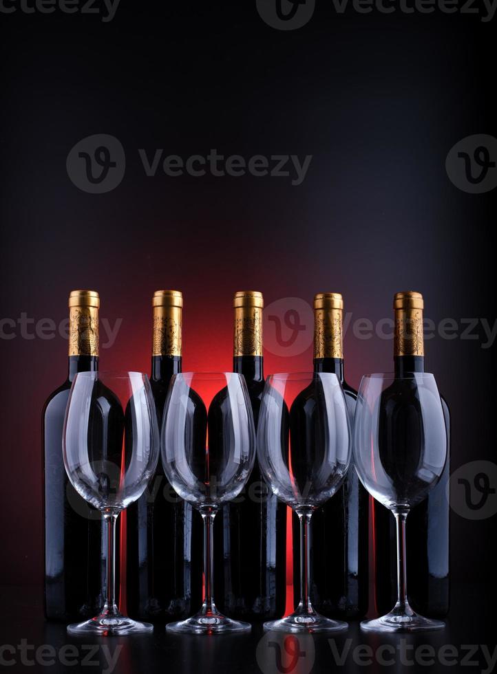 wijnflessen en vol glas met rode en zwarte achtergrond foto