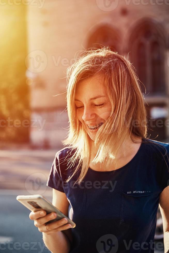 vrouw met een beugel gebruik makend van smartphone Bij stad straat foto