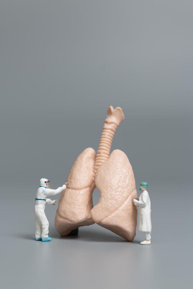 miniatuurdokters en verpleegsters die het concept met menselijke longen, virussen en bacteriën observeren en bespreken foto