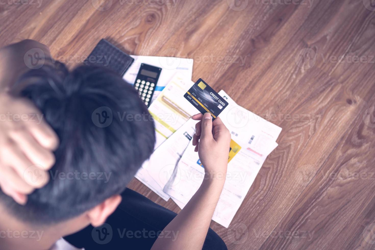 close-up iemands hand met een creditcard met papieren en een rekenmachine aan een bureau foto