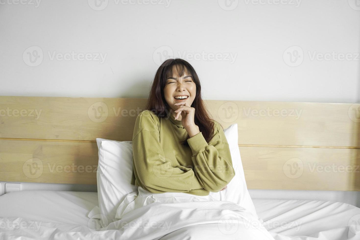 een attent jong Aziatisch vrouw is op zoek terzijde en Holding haar kin terwijl zittend Aan de bed foto