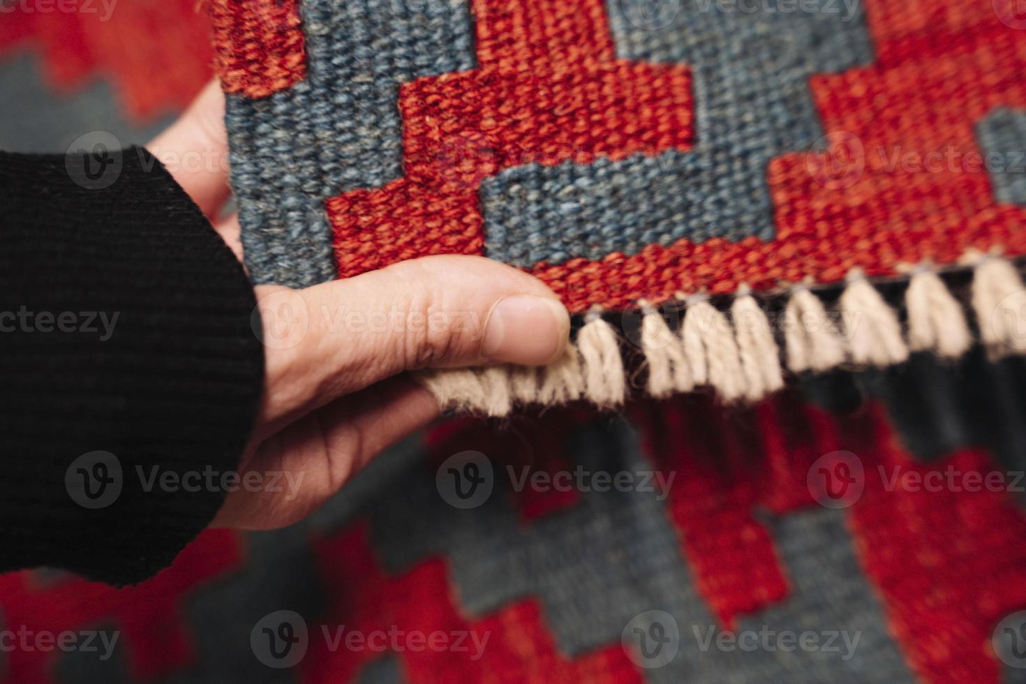 een vrouw hand- selecteert en accenten een gekleurde tapijt in een op te slaan foto