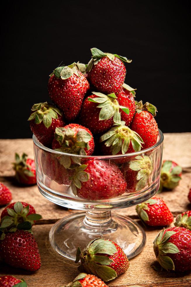 aardbeien in een glas en op een tafel foto