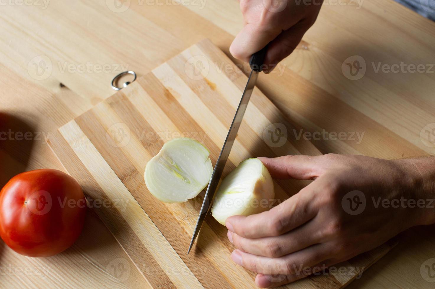 Mannen handen besnoeiing uien Aan een houten bord foto