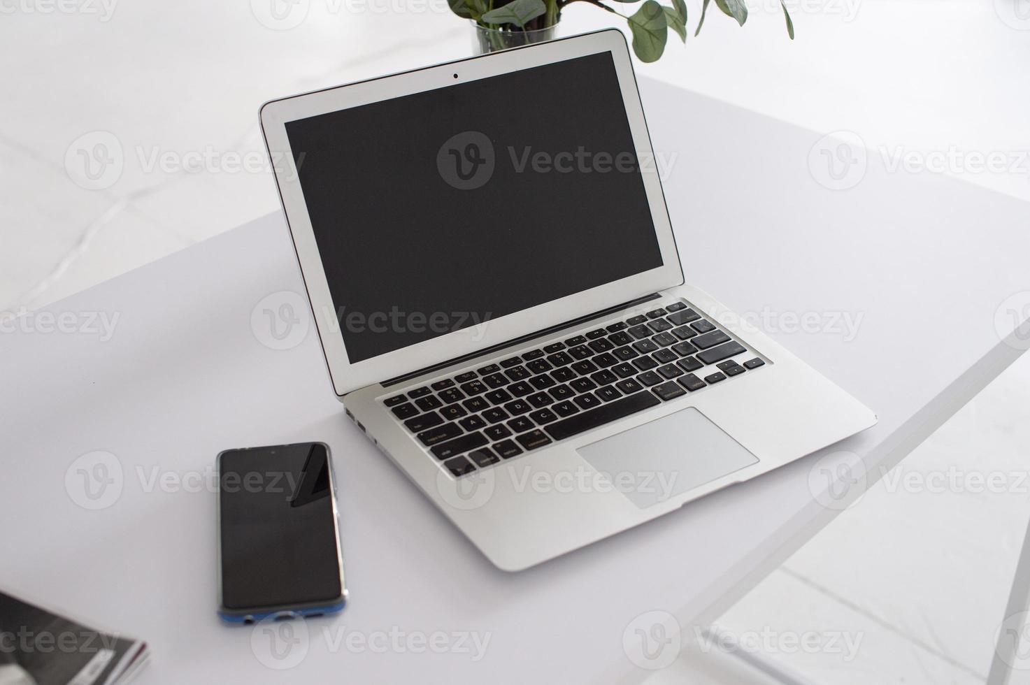 laptop Aan een wit tafel De volgende naar de telefoon foto