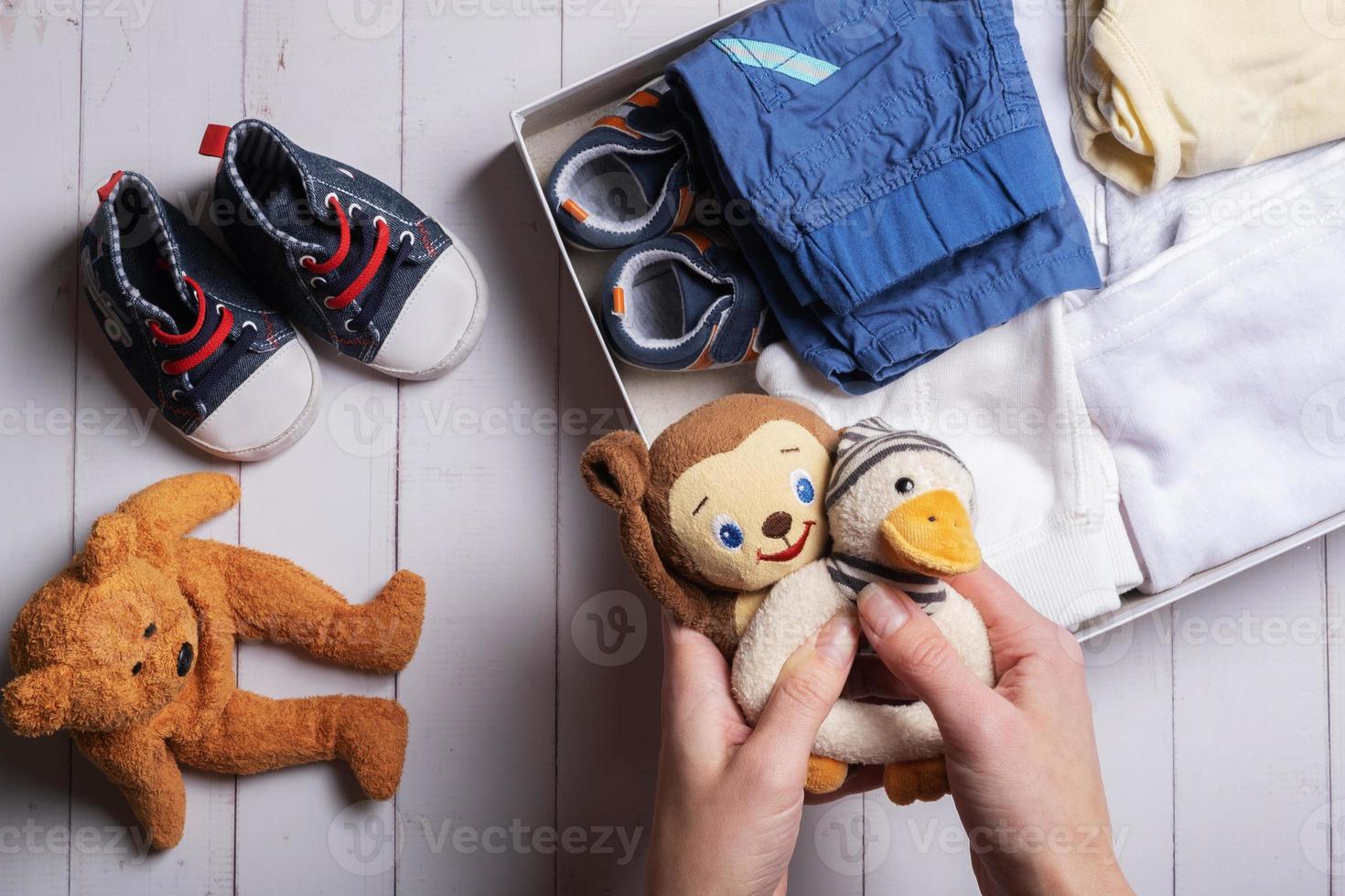 vrouw handen zetten kinderen speelgoed, kleren, schoenen in een bijdrage doos. tweede hand, kleding recycling concept foto