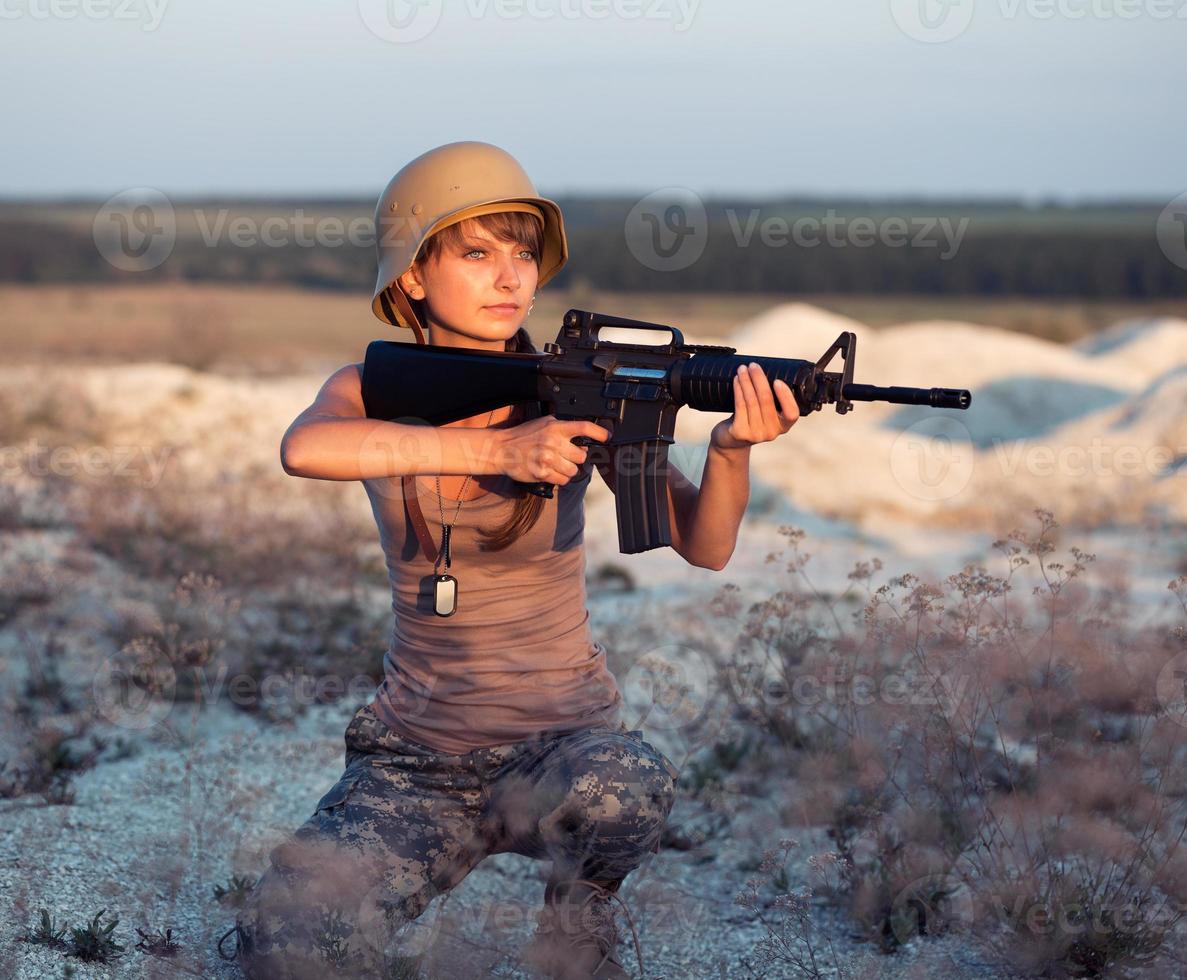 jong vrouw soldaat gekleed in een camouflage met een geweer in de buitenshuis foto