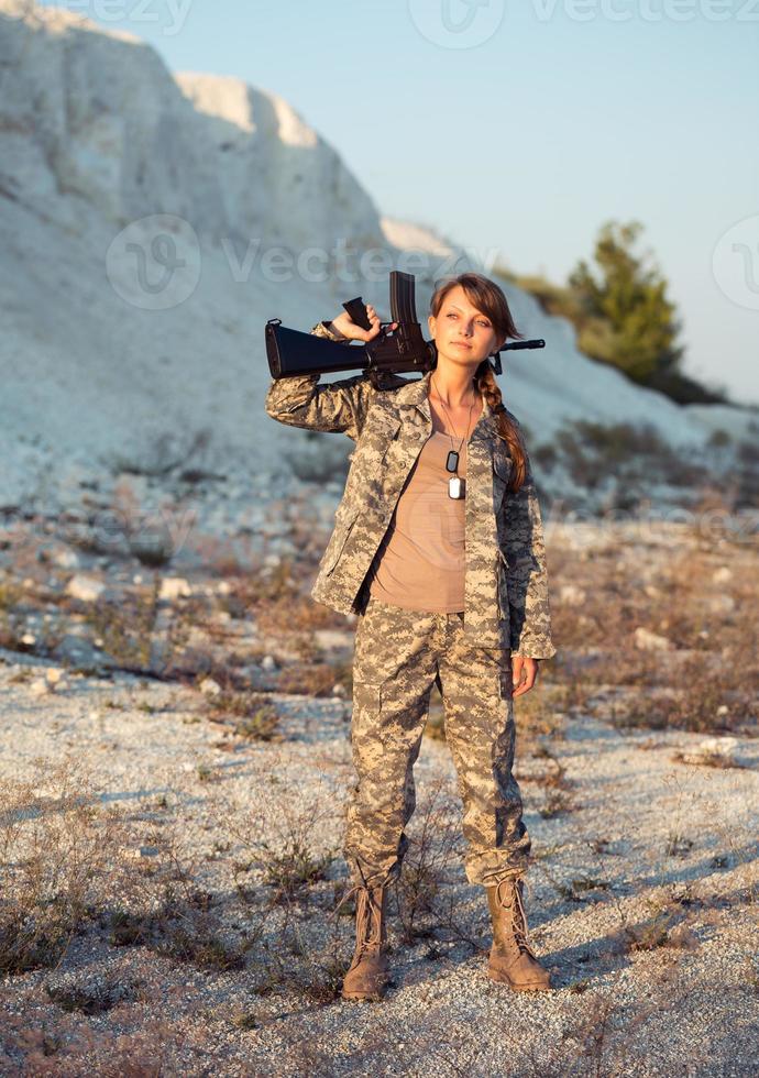 jong vrouw soldaat gekleed in een camouflage met een geweer in de plaats foto