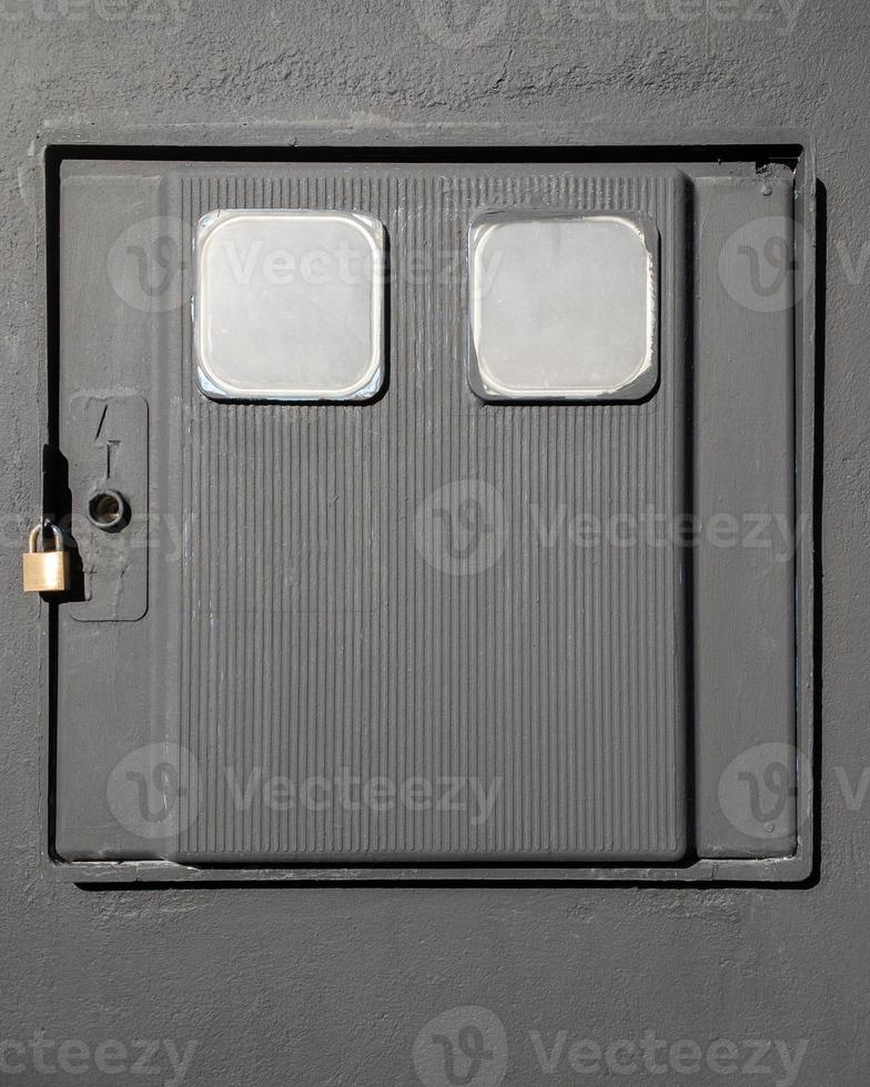 grijze doos voor elektrische meter met hangslot aan een muur foto