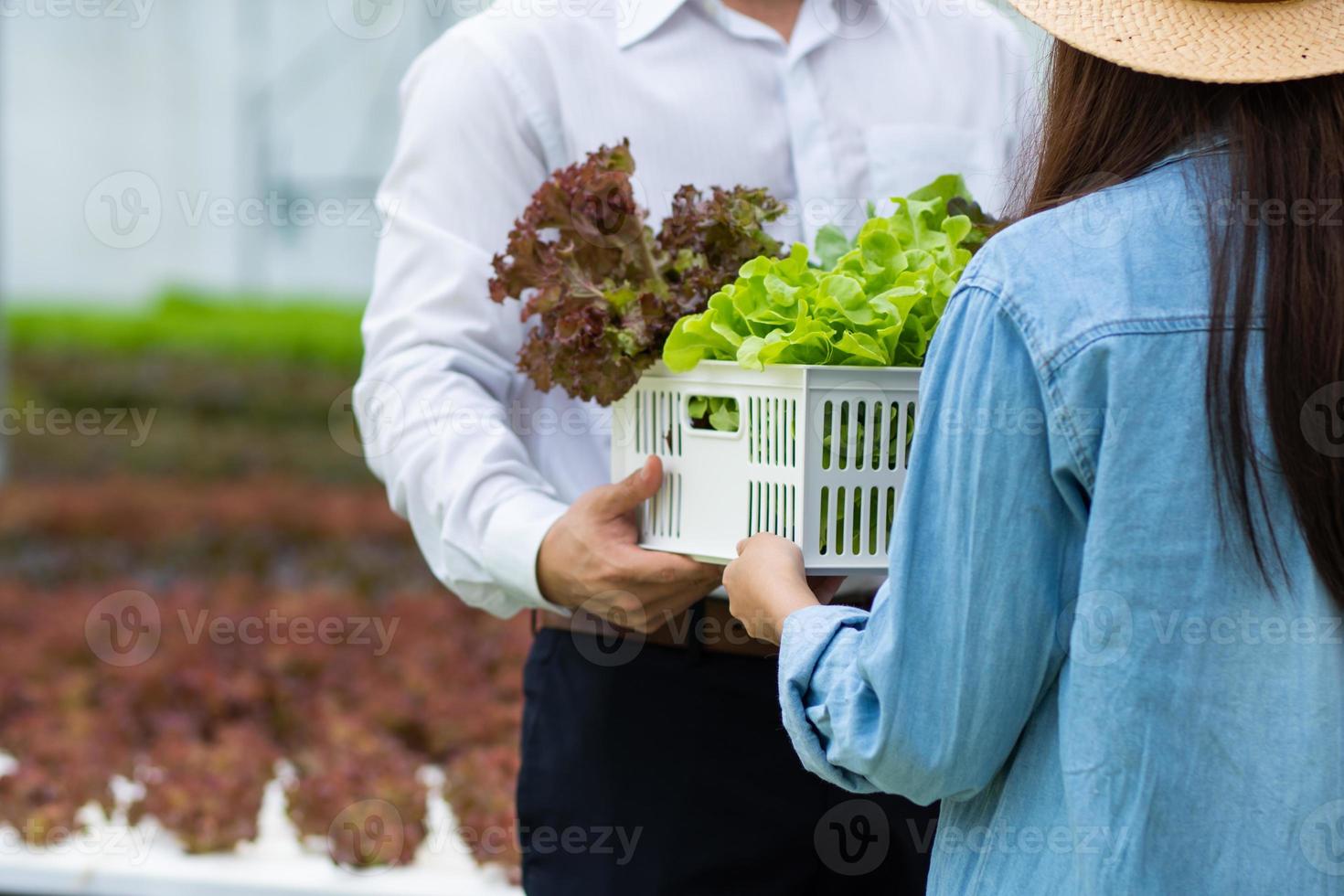 man en vrouw met krat met groenten in een kas foto