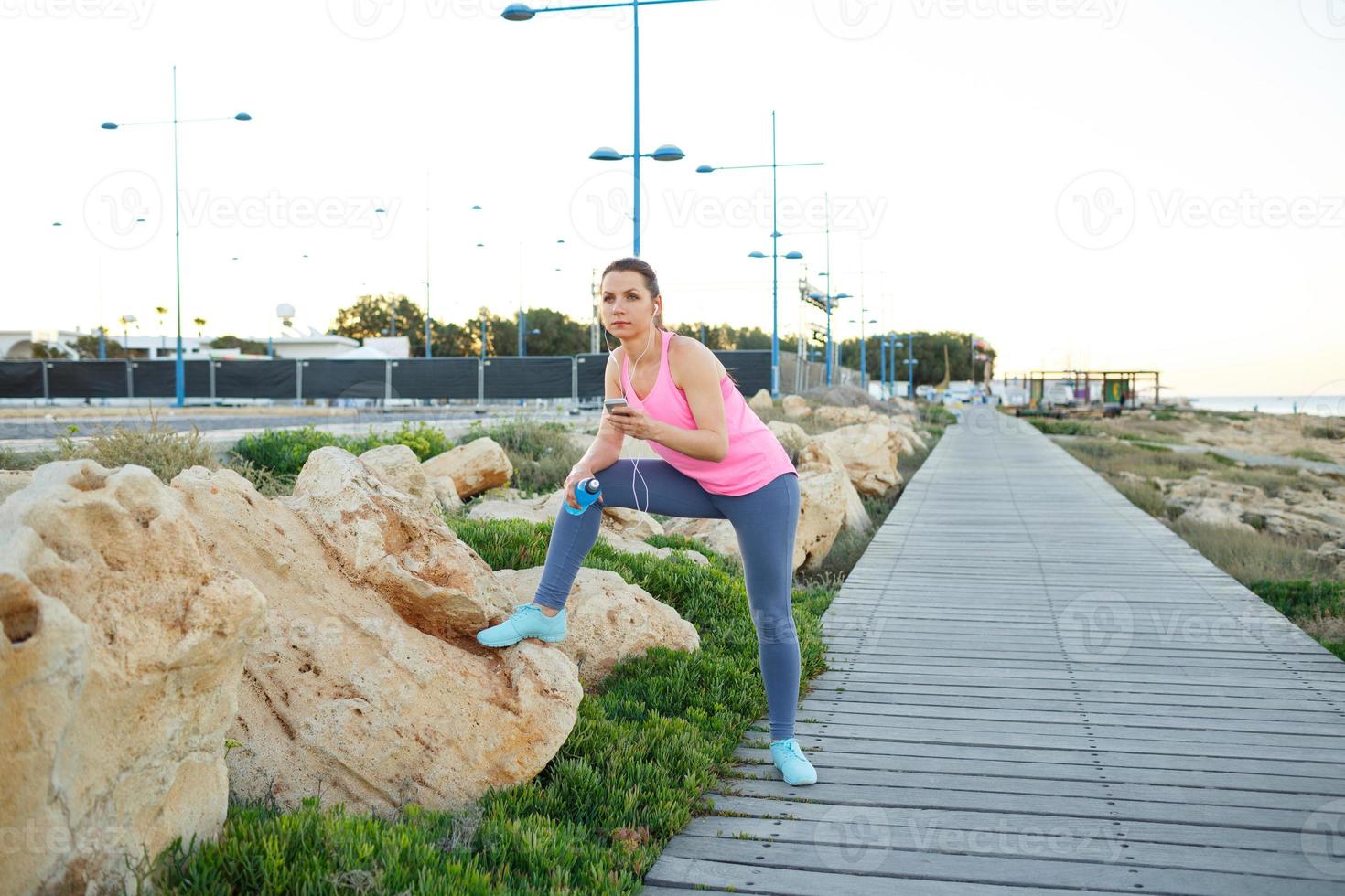 vrouw resting na jogging Aan een houten pad Bij de zee foto