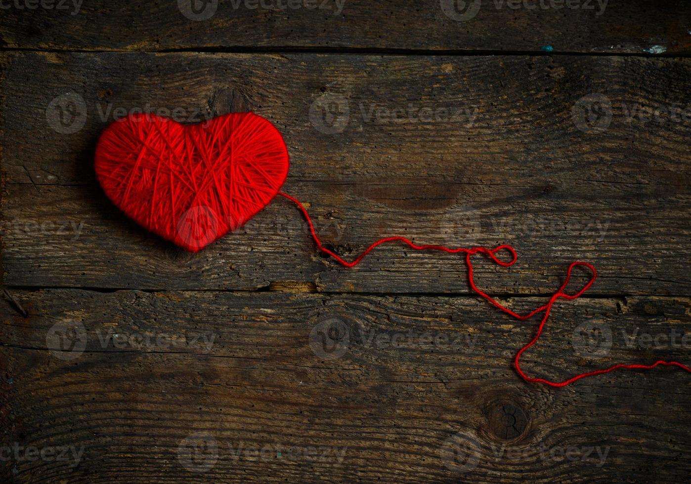 rood hart vorm gemaakt van wol Aan oud haveloos houten achtergrond foto