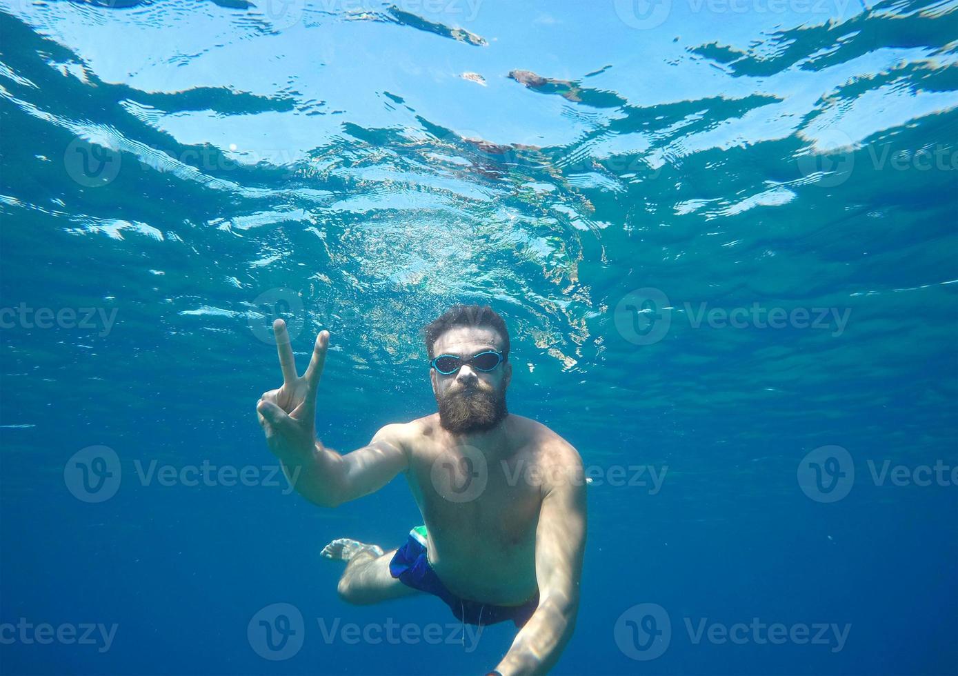Mens aan het doen onderwater- selfie schot met selfie stok foto