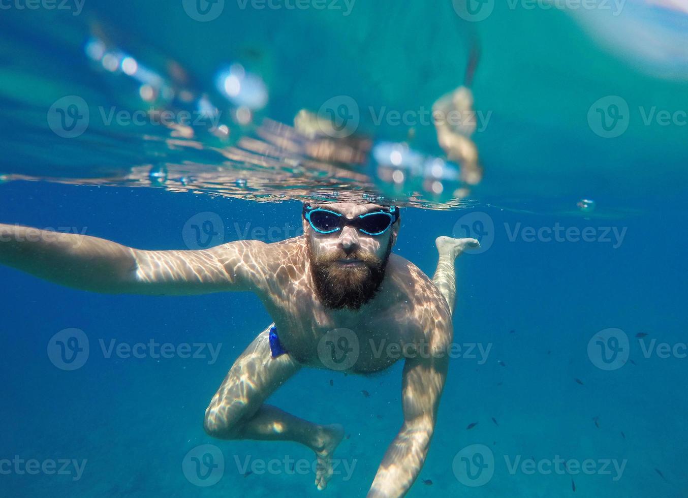 Mens aan het doen onderwater- selfie schot met selfie stok in blauw zee foto
