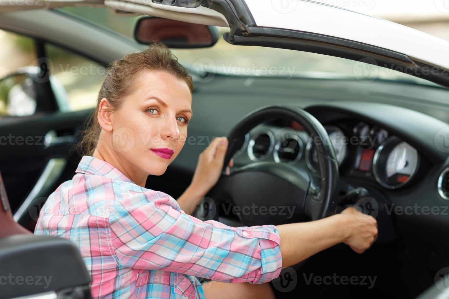 vrouw zittend in een converteerbaar en is gaan naar begin de motor foto