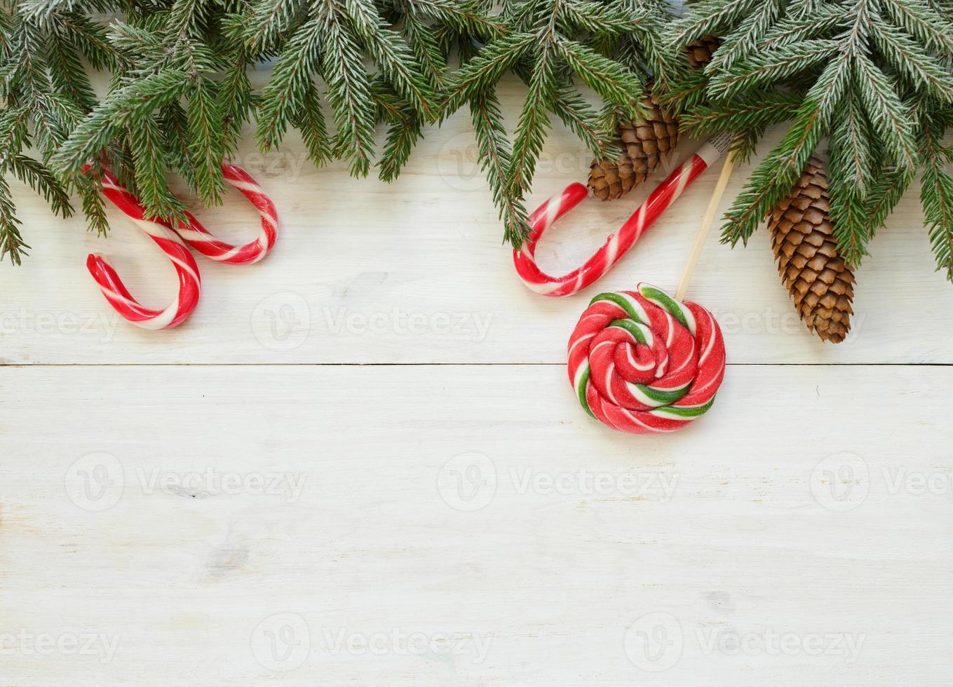 Kerstmis grens met Spar boom takken met kegels en snoep riet Aan wit houten borden klaar foto