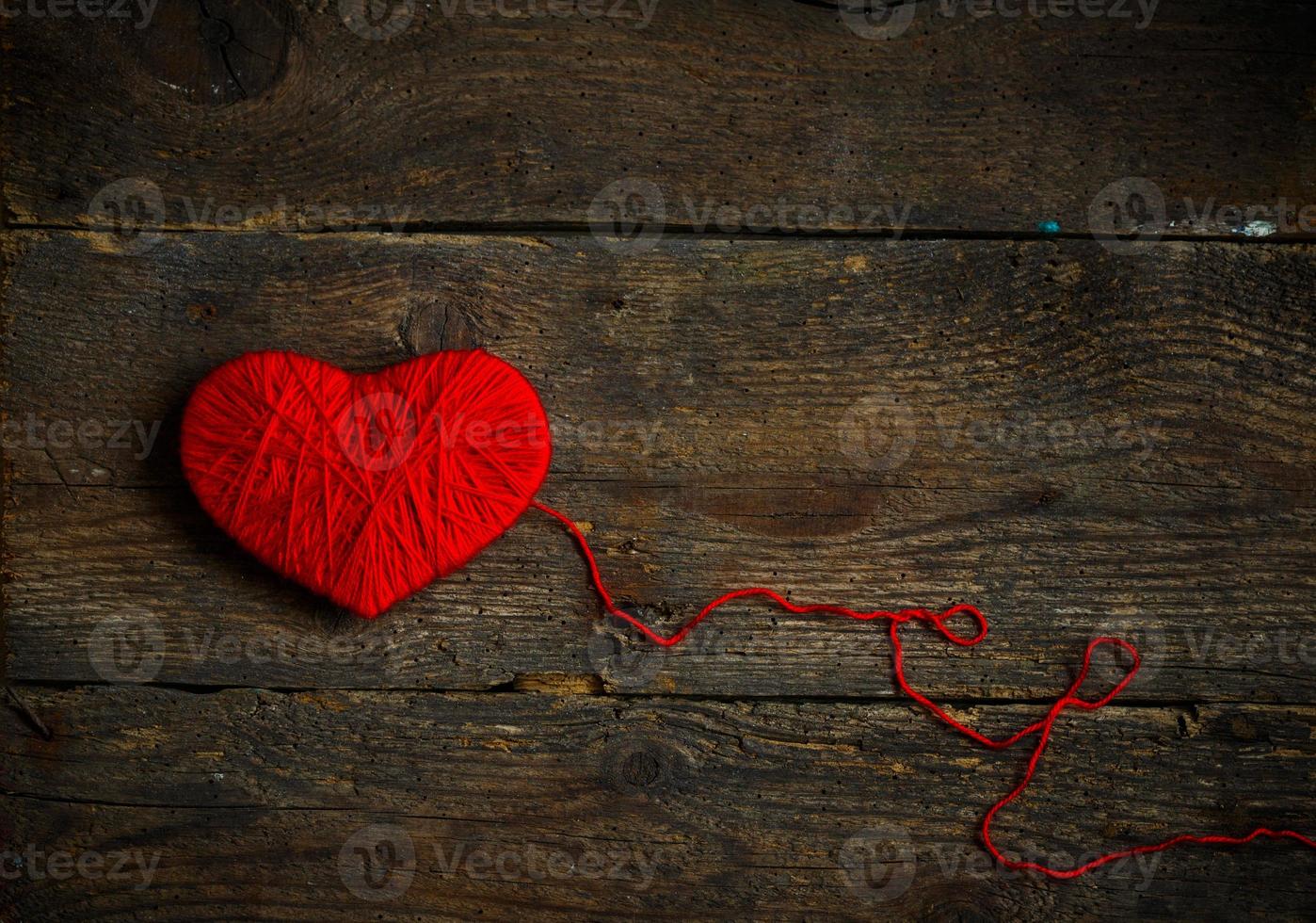 rood hart vorm gemaakt van wol Aan oud haveloos houten achtergrond foto