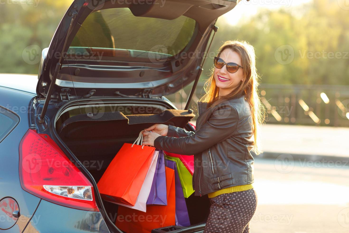 Kaukasisch vrouw zetten haar boodschappen doen Tassen in de auto romp foto