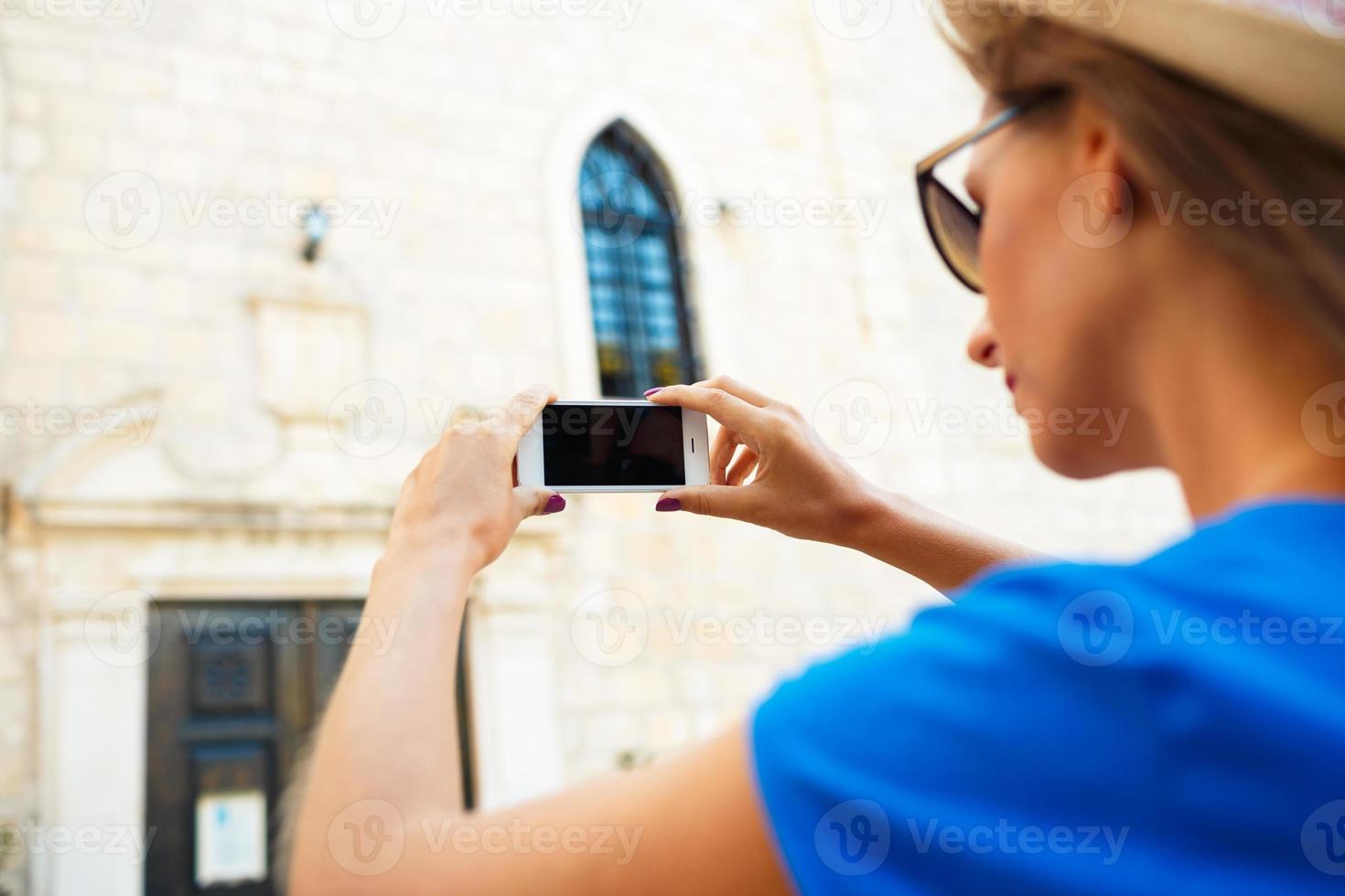 meisje in hoed maken foto's van een kerk door de smartphone foto