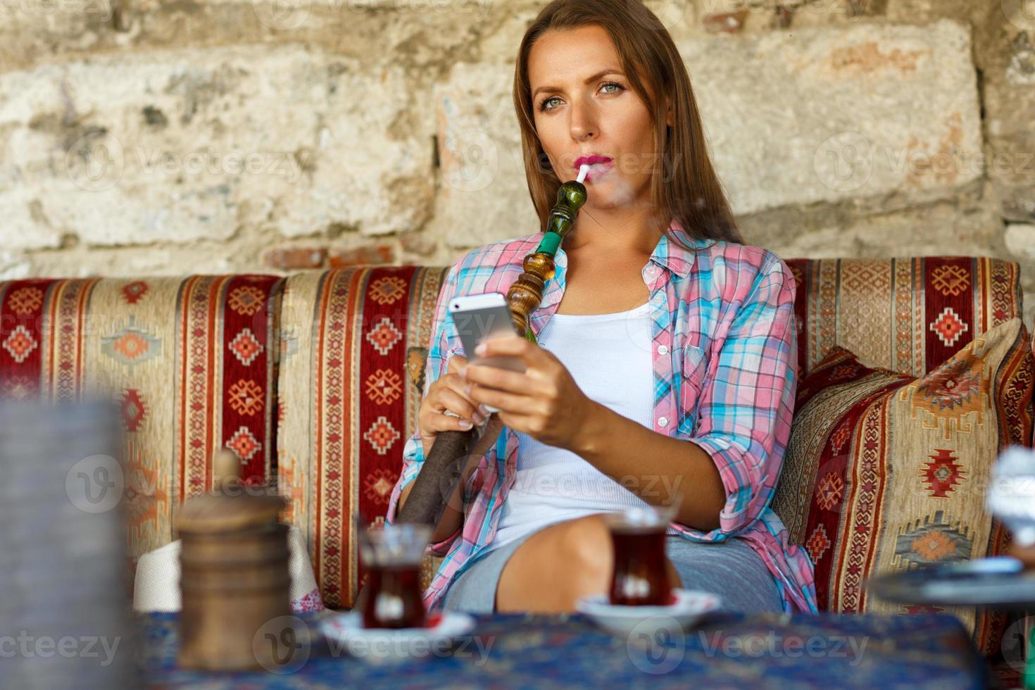 vrouw roken een hookah en toepassingen smartphone in een cafe in Istanbul, kalkoen foto