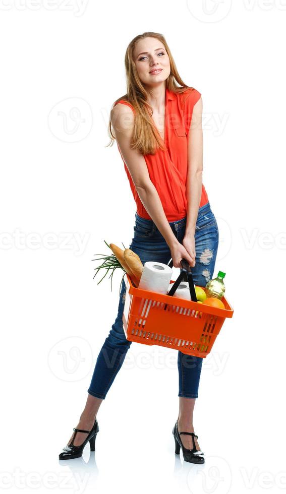 gelukkig vrouw Holding een mand vol van gezond voedsel. boodschappen doen foto