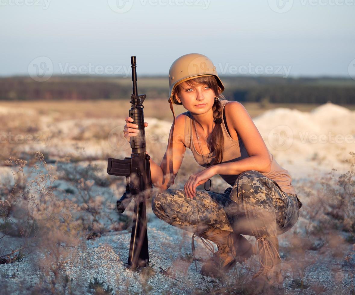 jong vrouw soldaat gekleed in een camouflage met een geweer in de buitenshuis foto