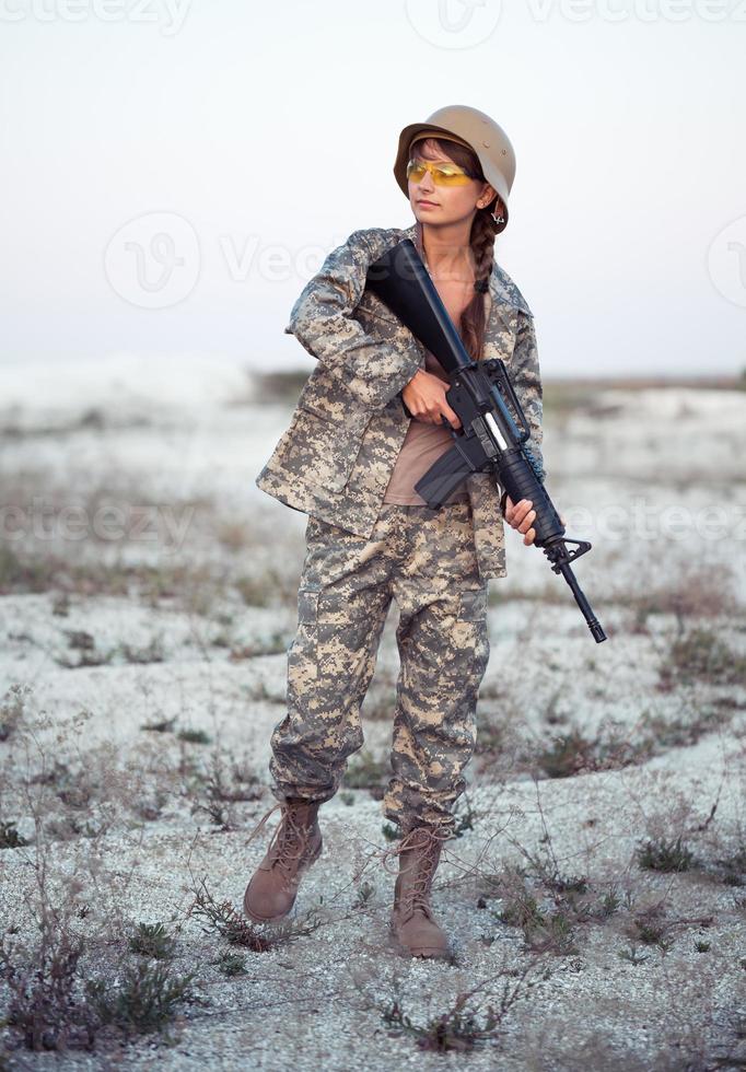 vrouw soldaat gekleed in een camouflage met een geweer in de buitenshuis foto