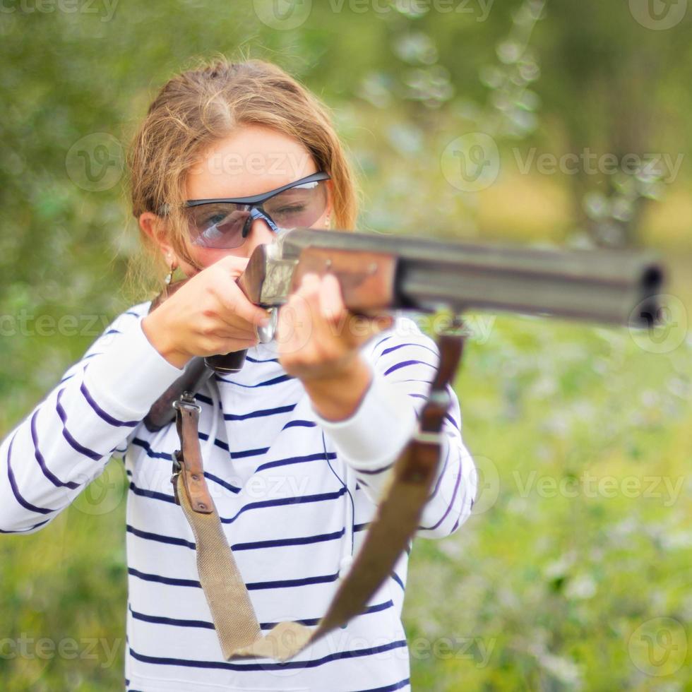 een jong meisje met een geweer voor val het schieten foto