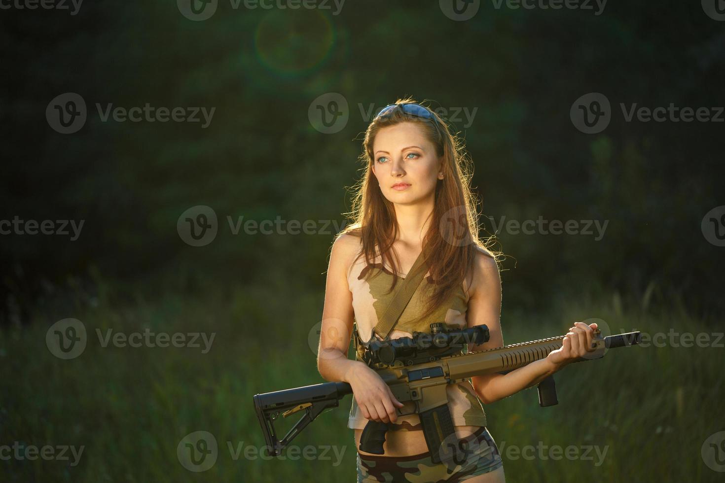 jong mooi meisje met een jachtgeweer in een buitenshuis foto