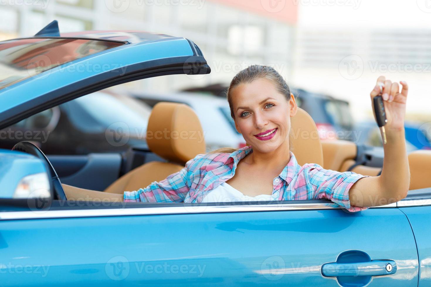 jong mooi vrouw zittend in een converteerbaar auto met de sleutels in hand- foto