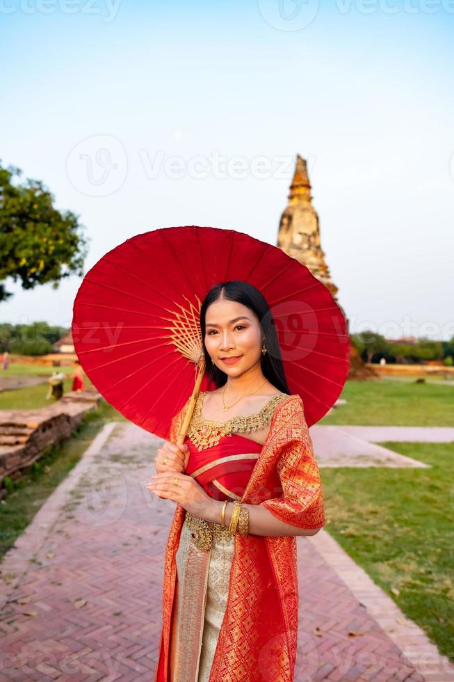 mooi Thais meisje in traditioneel jurk kostuum rood paraplu net zo Thais tempel waar is de openbaar plaats, Thais vrouw in traditioneel kostuum van Thailand. foto