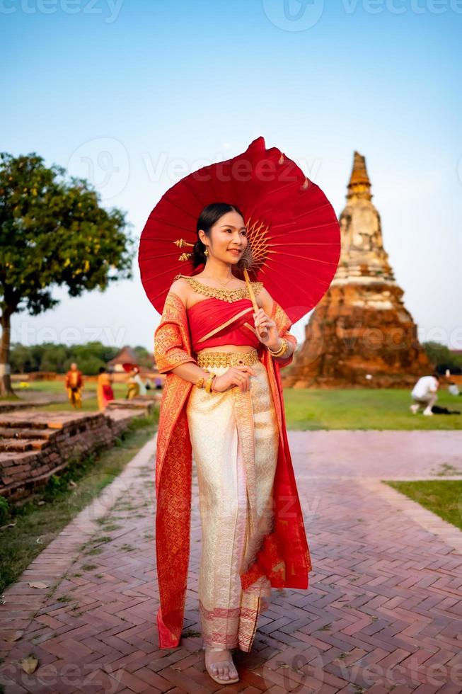 mooi Thais meisje in traditioneel jurk kostuum rood paraplu net zo Thais tempel waar is de openbaar plaats, Thais vrouw in traditioneel kostuum van Thailand. foto