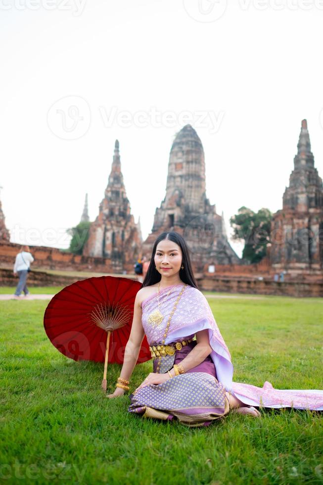 mooi Thais meisje in traditioneel jurk kostuum rood paraplu net zo Thais tempel waar is de openbaar plaats, Thais vrouw in traditioneel kostuum van Thailand. foto