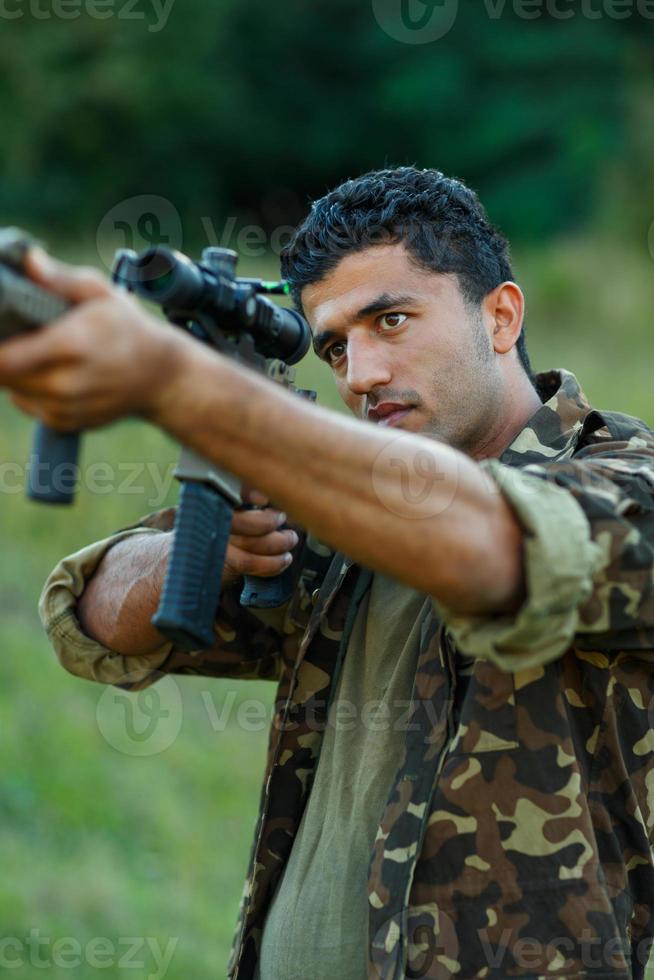 Mens van Arabisch nationaliteit in camouflage met een geweer het richten Bij een doelwit foto