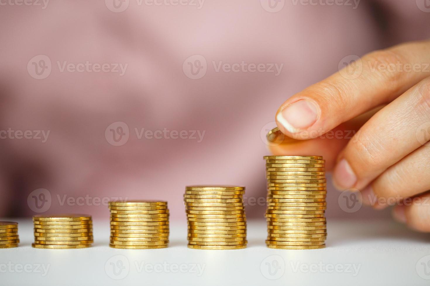 vrouw hand- stapelen goud munten in toenemend kolommen foto