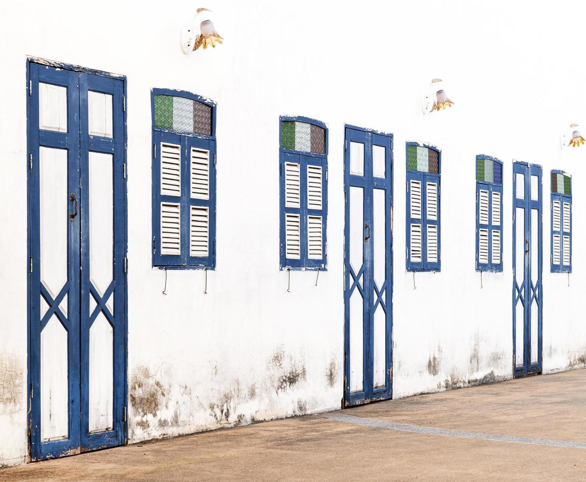 blauw houten deur en venster patroon rij Aan oud wit muur achtergrond foto