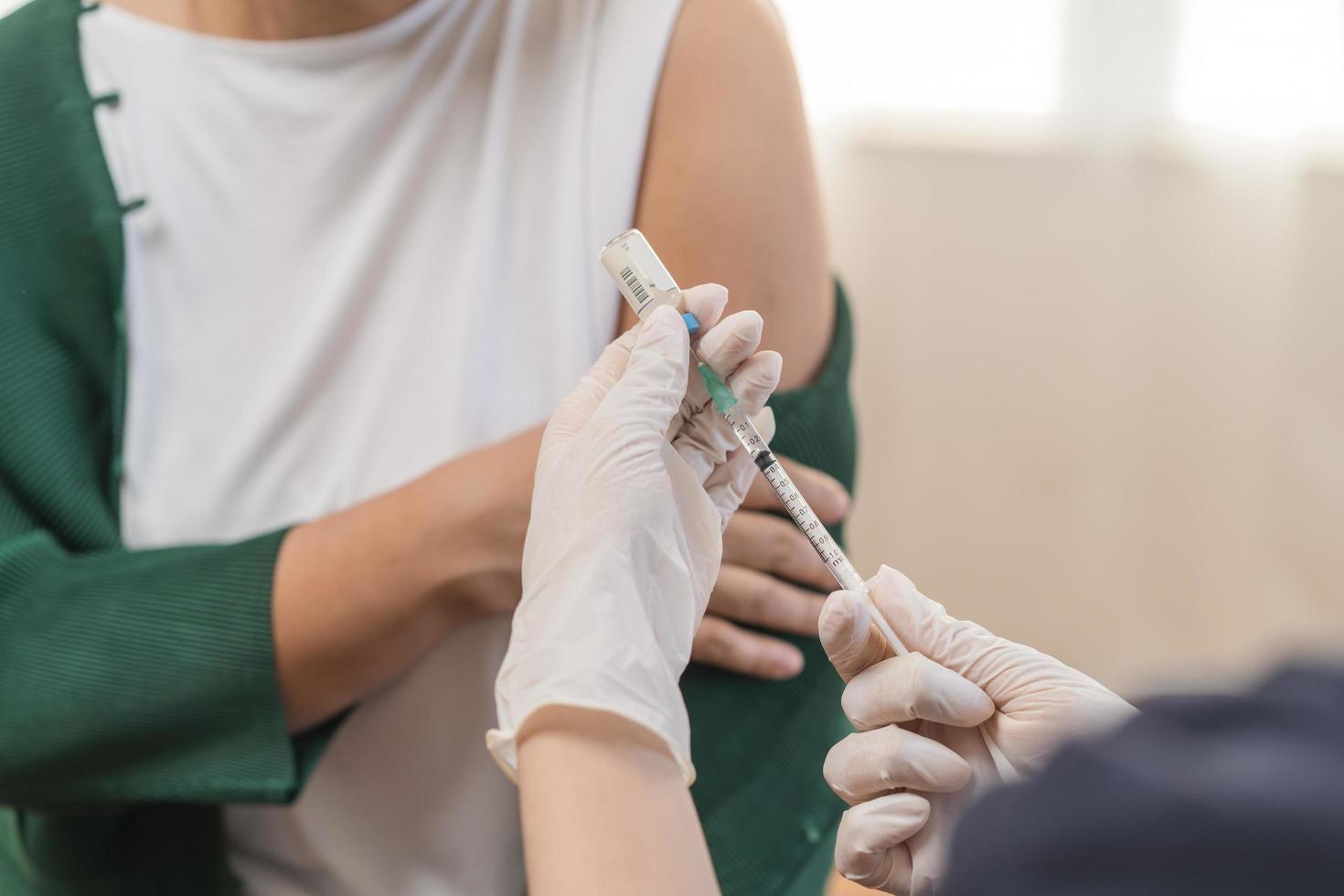 covid-19, coronavirus, ouderen Aziatisch volwassen vrouw krijgen vaccin van dokter of verpleegster geven schot naar volwassen geduldig Bij kliniek. gezondheidszorg, immunisatie, ziekte het voorkomen tegen griep of virus pandemisch foto