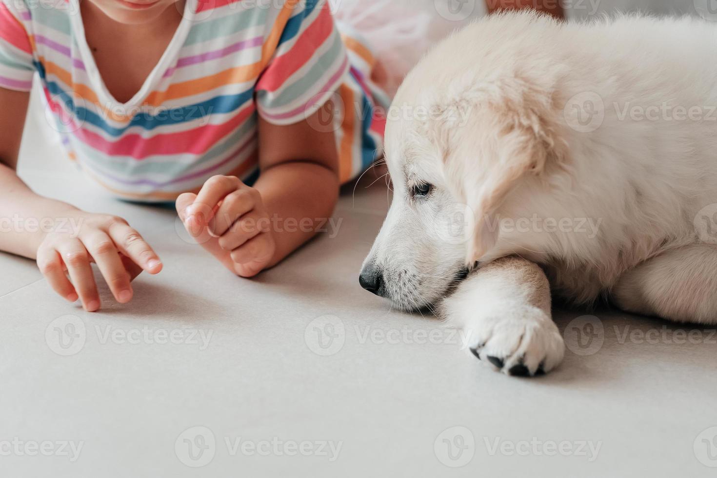 kind meisje en puppy huisdier hond gouden retriever liggen samen Aan verdieping kopiëren ruimte focus Aan hond vriendschap voor kinderen wit beige natuurlijk pastel colores keramisch of porselein schoon verdieping tegel foto