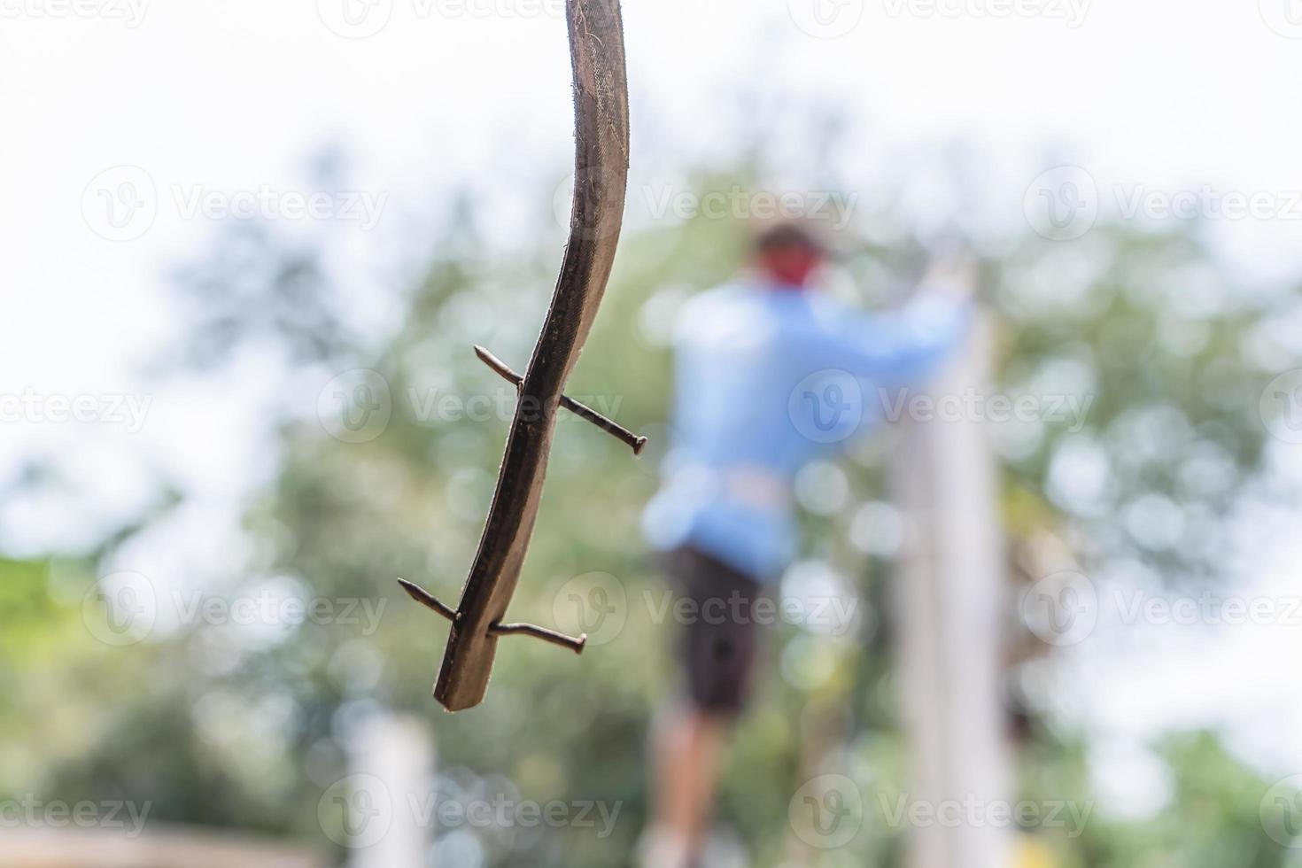 detailopname schot van roestig nagel Aan een houten plank hangende met wazig bouw arbeider staand en groen natuur achtergrond. abstract achtergrond foto