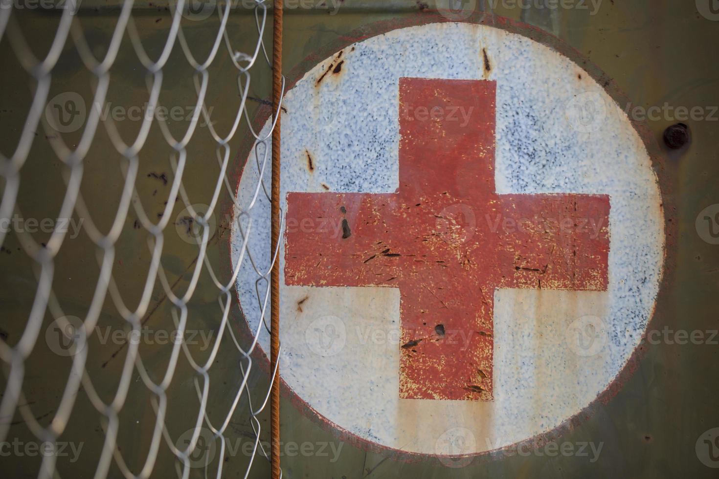 medisch rood kruis Aan een schuur roestig muur. foto