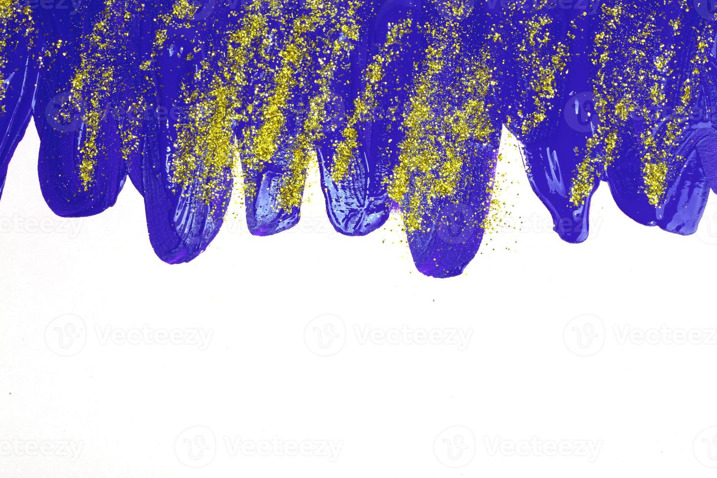 Aan een wit achtergrond, blauw iriserend vlekken van vloeiende acryl verf met goud schittert. foto