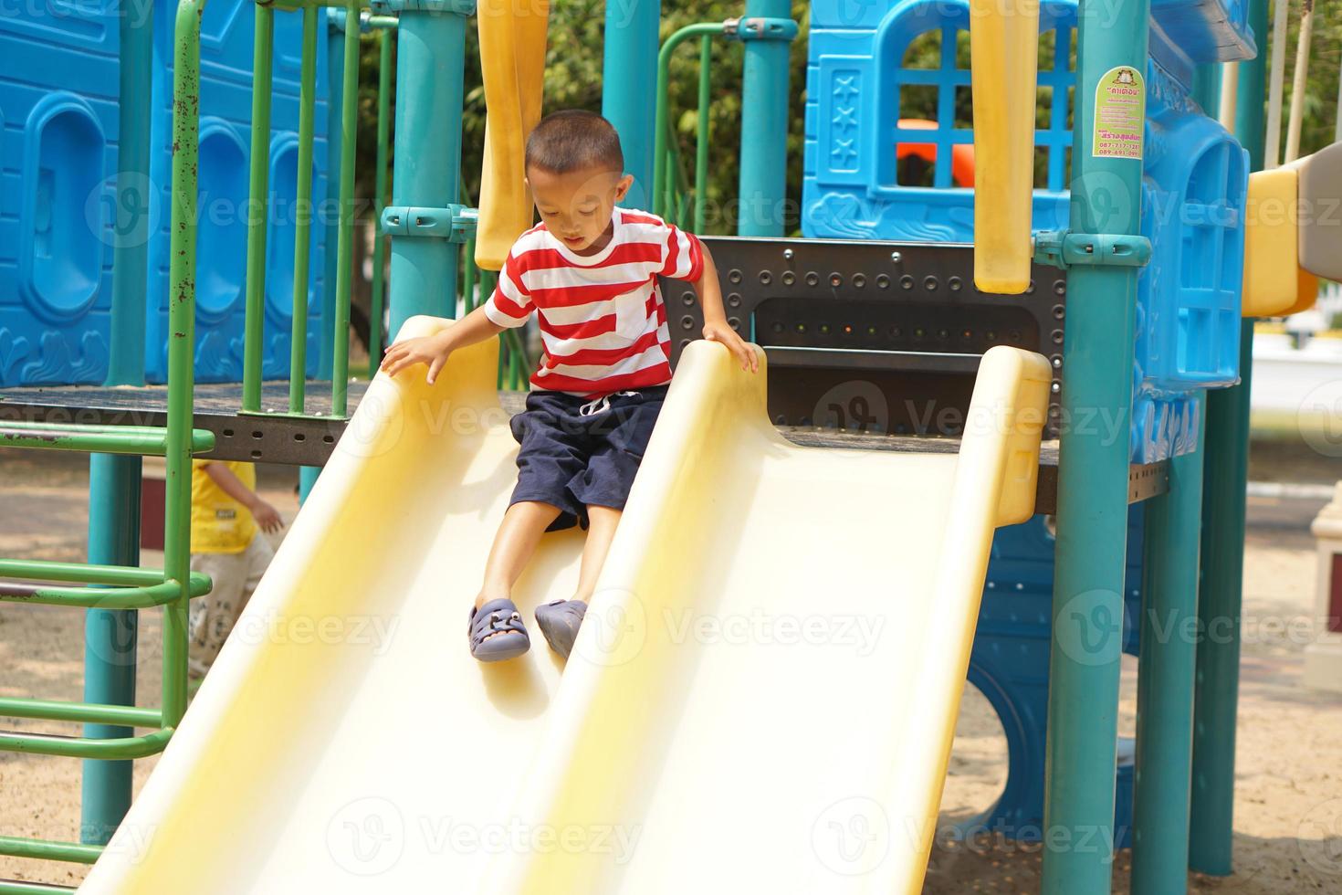 jongen spelen in de speelplaats in de park foto
