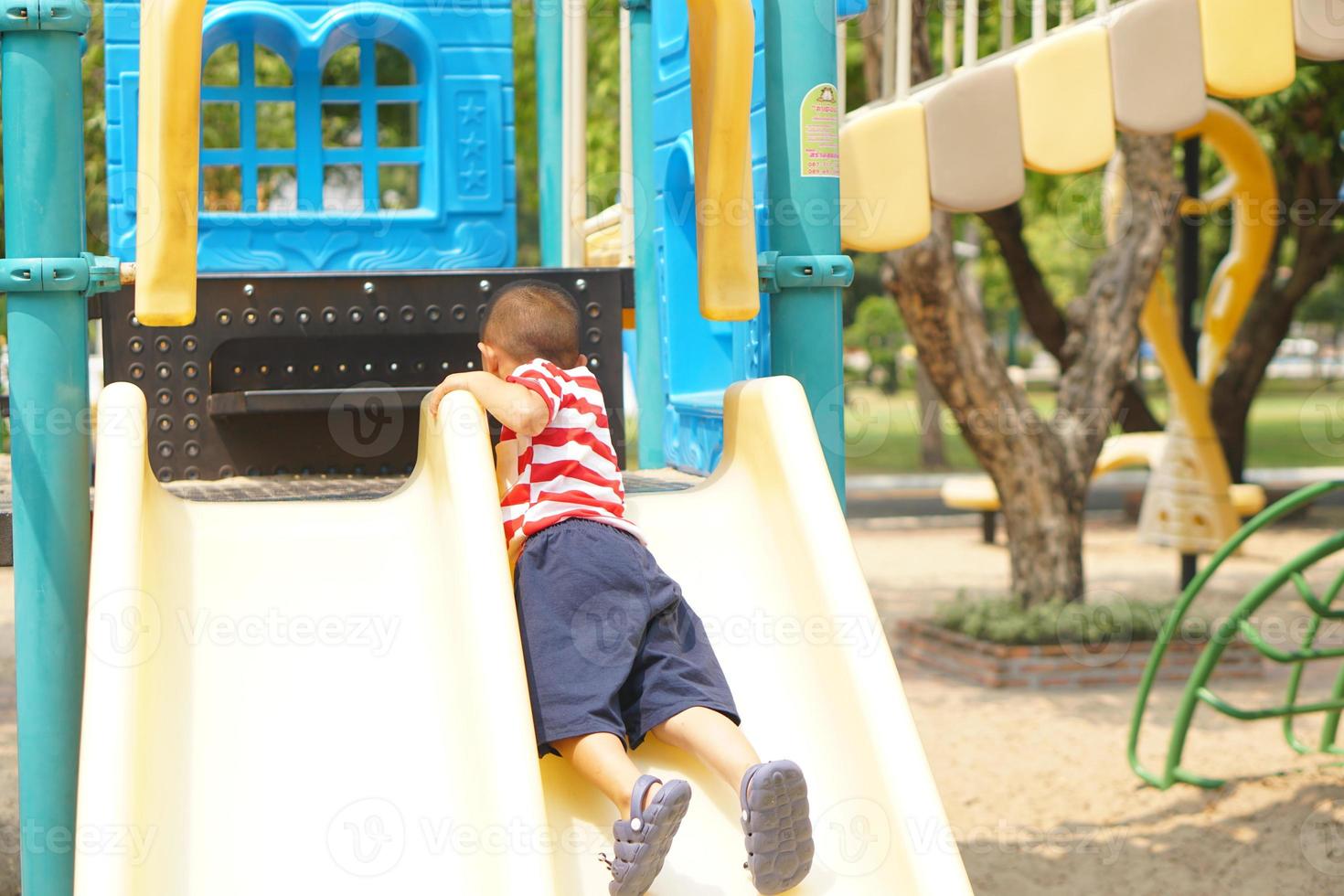 jongen spelen in de speelplaats in de park foto