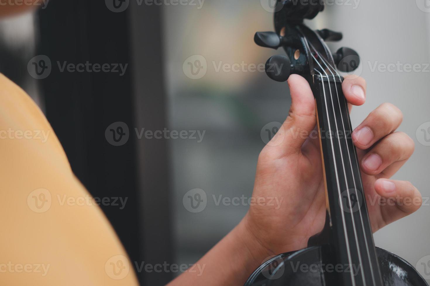 een klein Aziatisch kind speelt en oefent viool muzikaal snaarinstrument tegen in huis, concept van muzikaal onderwijs, inspiratie, tiener kunstacademie student. foto