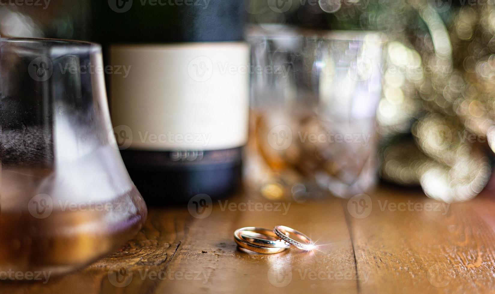 bruiloft ringen Aan rustiek houten tafel met Scotch en Champagne. foto