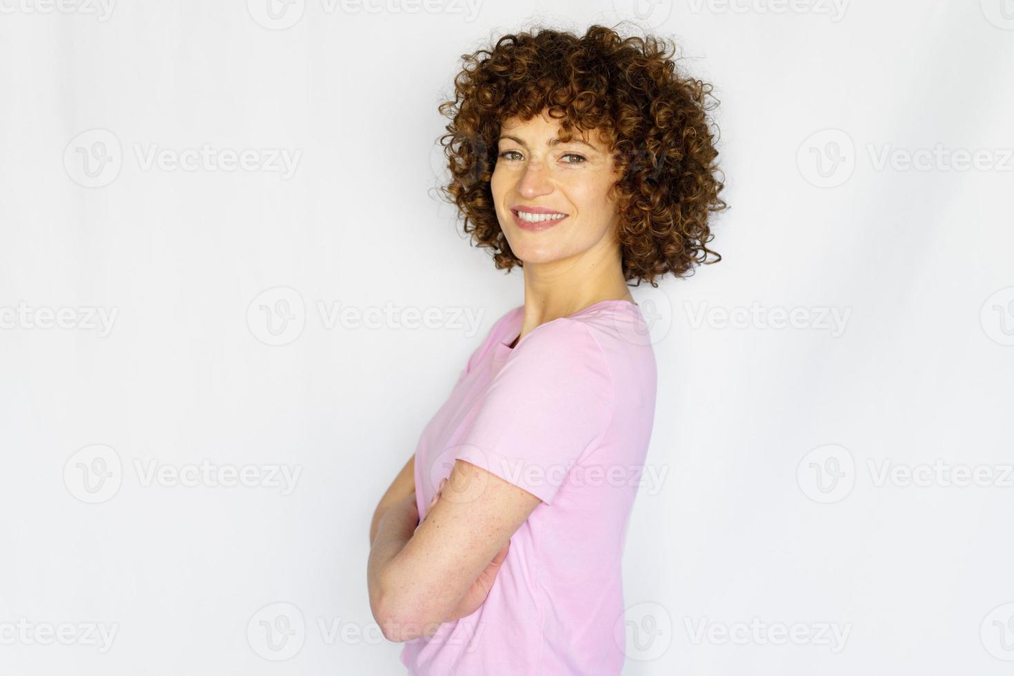 glimlachen vrouw met gekruld haar- met armen gevouwen in gewoontjes kleding foto