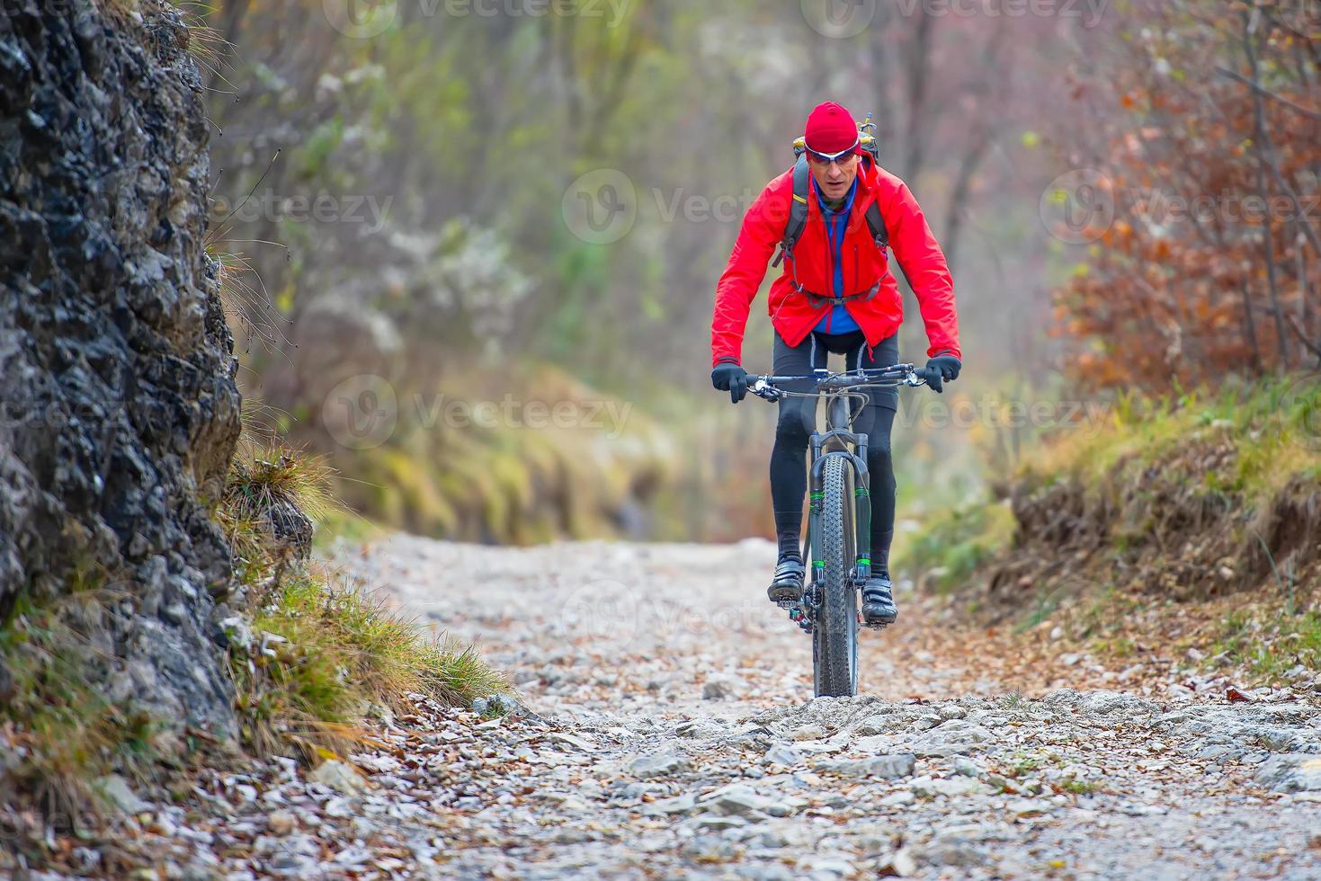 fietser met mountainbike bergafwaarts op onverharde weg in de herfst foto